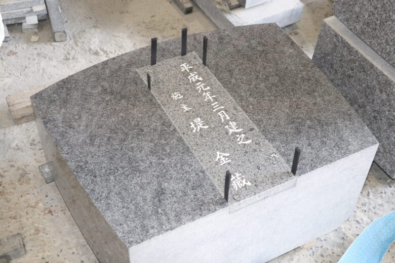 旧墓所のサオ石の文字彫刻部分を新墓所のサオ石背面に組み込む。彫刻部分には白色を入れた（㈱古市石材店）。