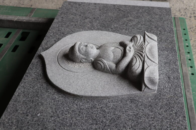 カロートの石に陽刻された阿弥陀如来像（庵治石細目、山田忠石材店香川県高松市）。